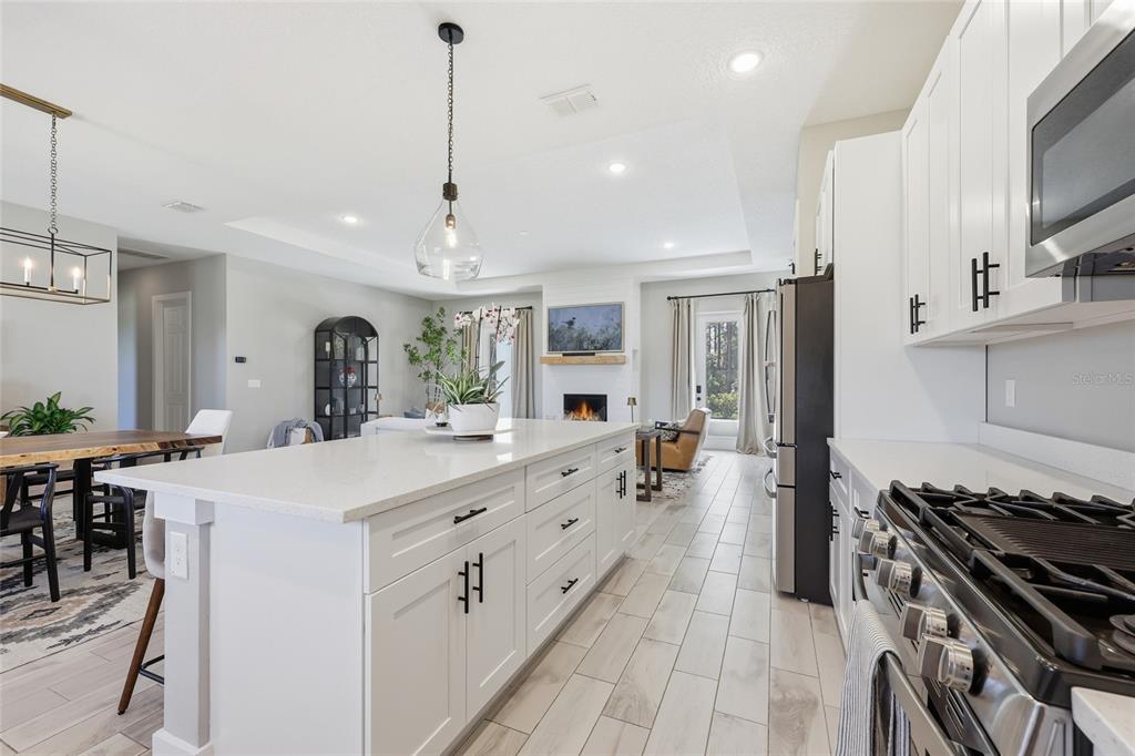 A modern kitchen with a large white island, quartz countertops, and stainless steel appliances — 5777 SW 140TH AVENUE, OCALA, FL