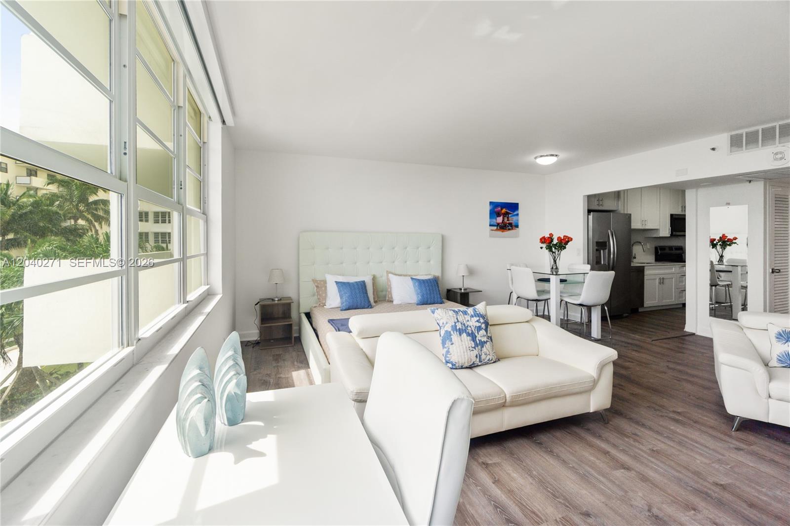 A studio apartment features a bed, white sofa, dining area, and kitchen with wood flooring — 100 Lincoln Rd # 538, Miami Beach FL 33139, MIAMI BEACH, FL