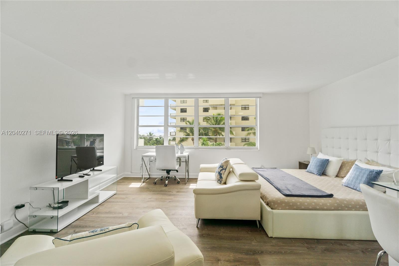 A bedroom features a white bed, a sofa, a desk, and a television console — 100 Lincoln Rd # 538, Miami Beach FL 33139, MIAMI BEACH, FL