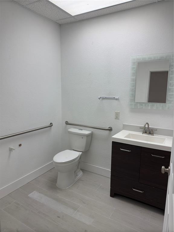 A bathroom features a toilet with grab bars, a dark wood vanity, and light flooring — 17880 TOLEDO BLADE BOULEVARD, PORT CHARLOTTE, FL