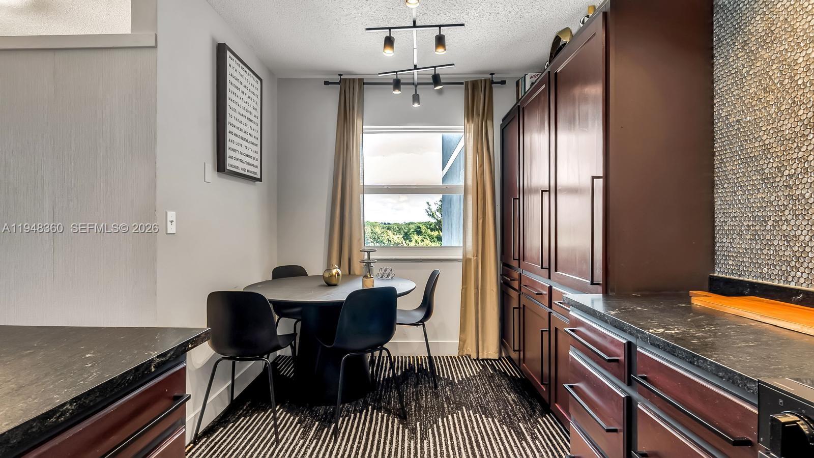 A dining area features a round table, black chairs, dark cabinetry, and a patterned rug — 3800 Hillcrest Dr # 401, Hollywood FL 33021, HOLLYWOOD, FL