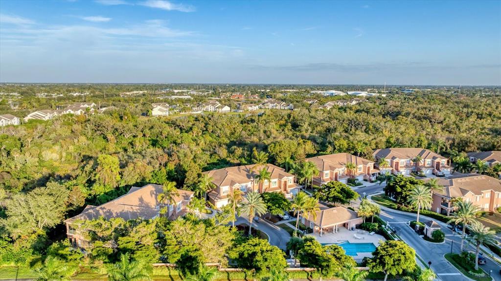An aerial view shows multi-story residential buildings surrounded by dense trees and a swimming pool — 5421 46TH COURT W, BRADENTON, FL