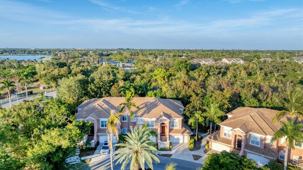 An aerial view shows two multi-story residential buildings surrounded by dense trees and greenery — 5421 46TH COURT W, BRADENTON, FL