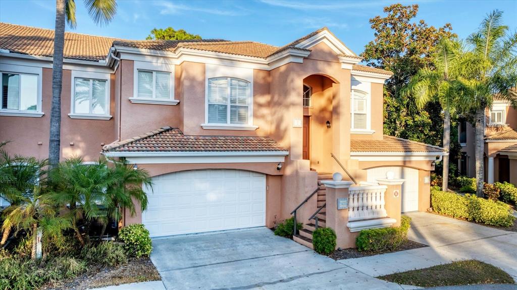 A two-story peach-colored house features a white garage door and an elevated front entrance — 5421 46TH COURT W, BRADENTON, FL