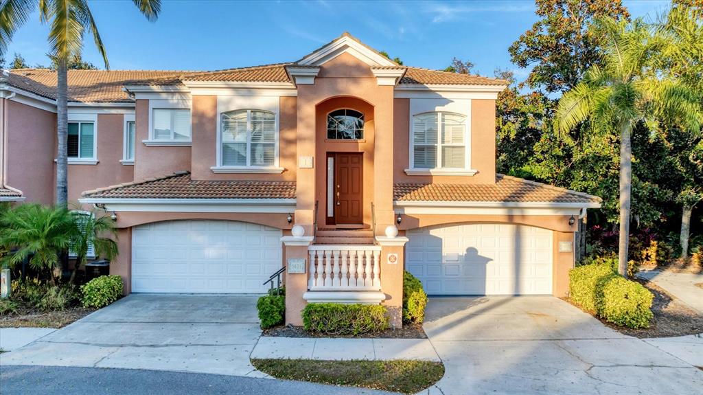 A two-story peach-colored house features two garage doors, a central entryway, and palm trees — 5421 46TH COURT W, BRADENTON, FL