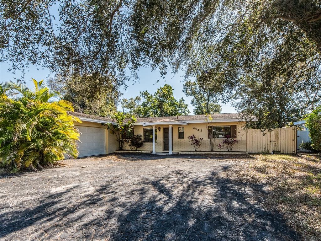 A single-story house with a beige brick facade, a front porch, and a paved driveway — 2242 INDIAN AVENUE S, LARGO, FL