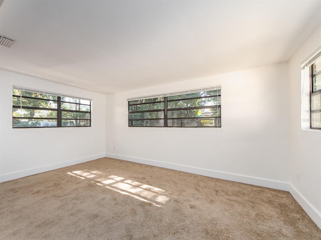 An empty room with beige carpet, white walls, and three windows with horizontal blinds — 2242 INDIAN AVENUE S, LARGO, FL