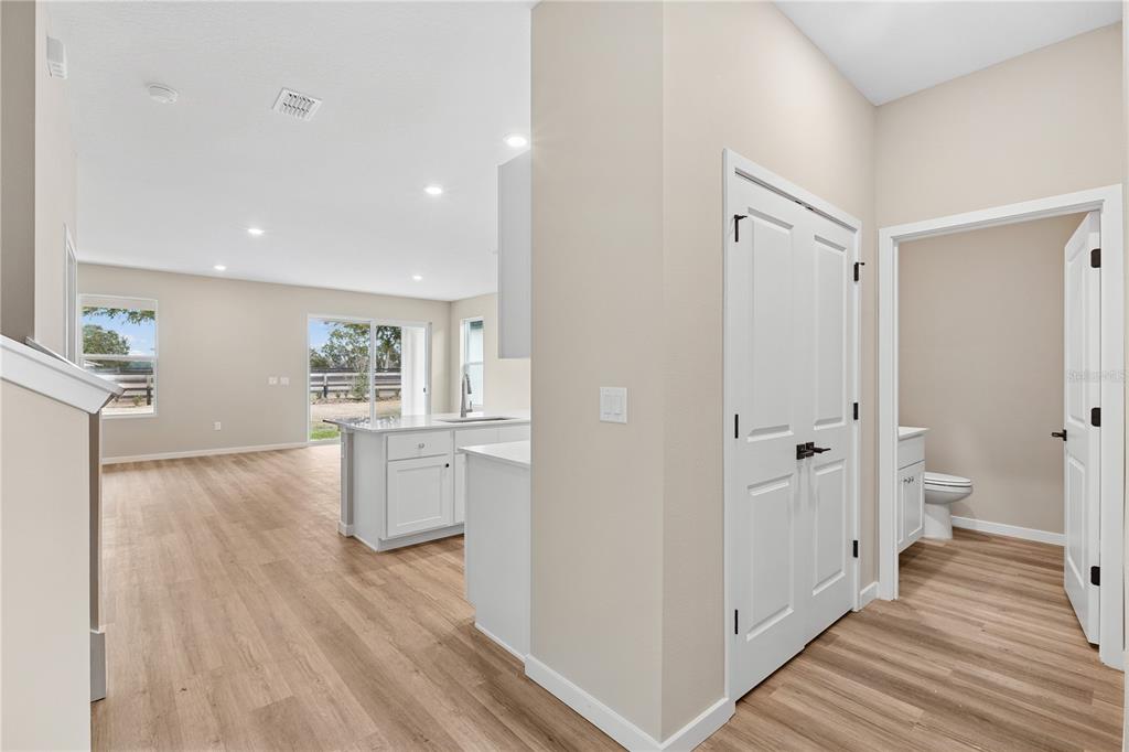A view of a kitchen and living area with light wood floors and white cabinets — 4465 NW 37TH STREET ROAD, OCALA, FL