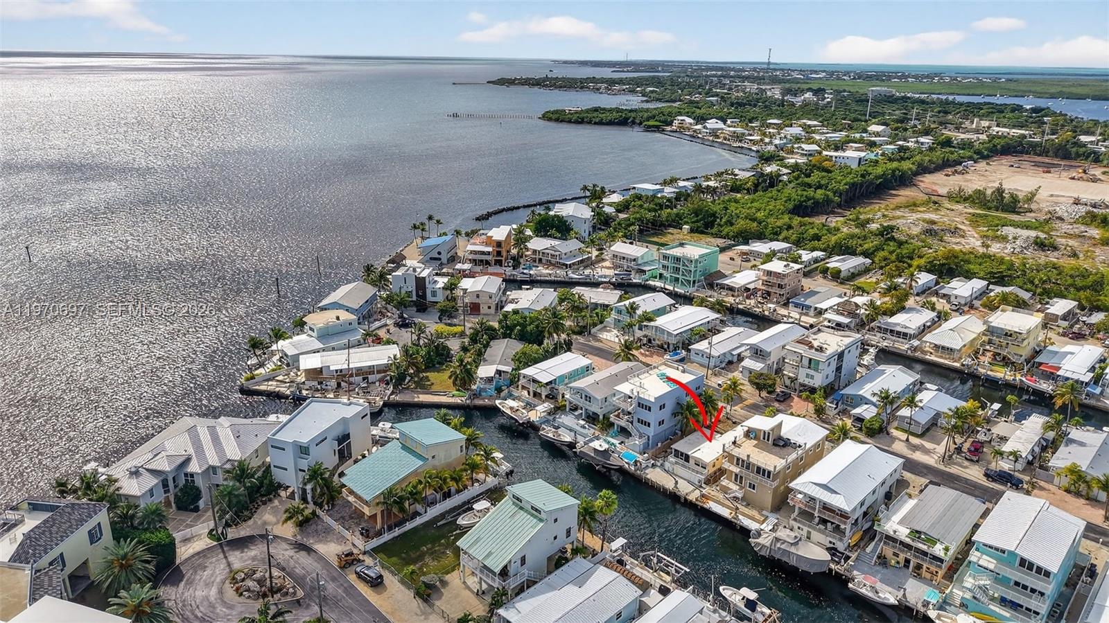 An aerial view shows a canal-front neighborhood with houses, docks, and boats — 261 Burgundy Dr, Tavernier FL 33070, TAVERNIER, FL