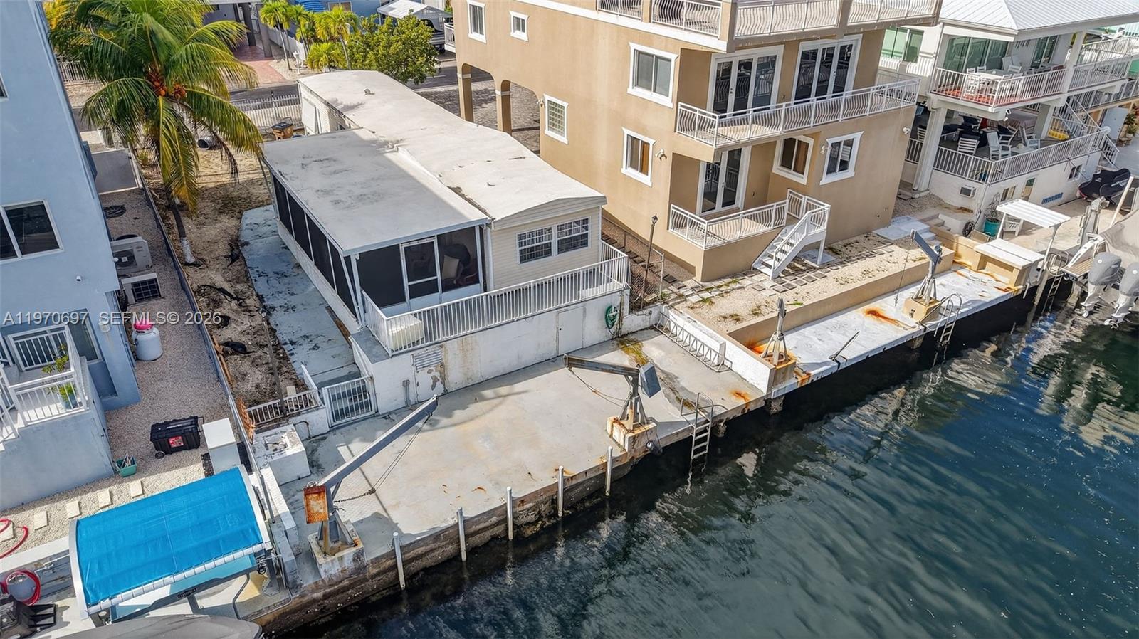 An aerial view shows a mobile home with a deck and boat lift on a canal — 261 Burgundy Dr, Tavernier FL 33070, TAVERNIER, FL