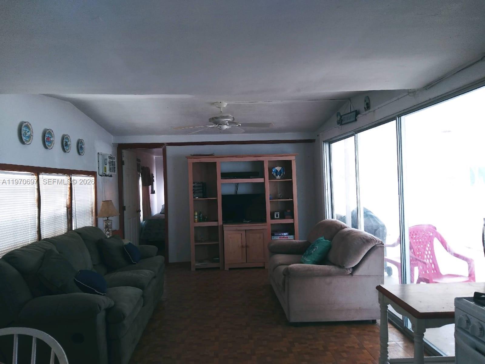 A living room features two sofas, a wooden entertainment center, and large sliding glass doors — 261 Burgundy Dr, Tavernier FL 33070, TAVERNIER, FL