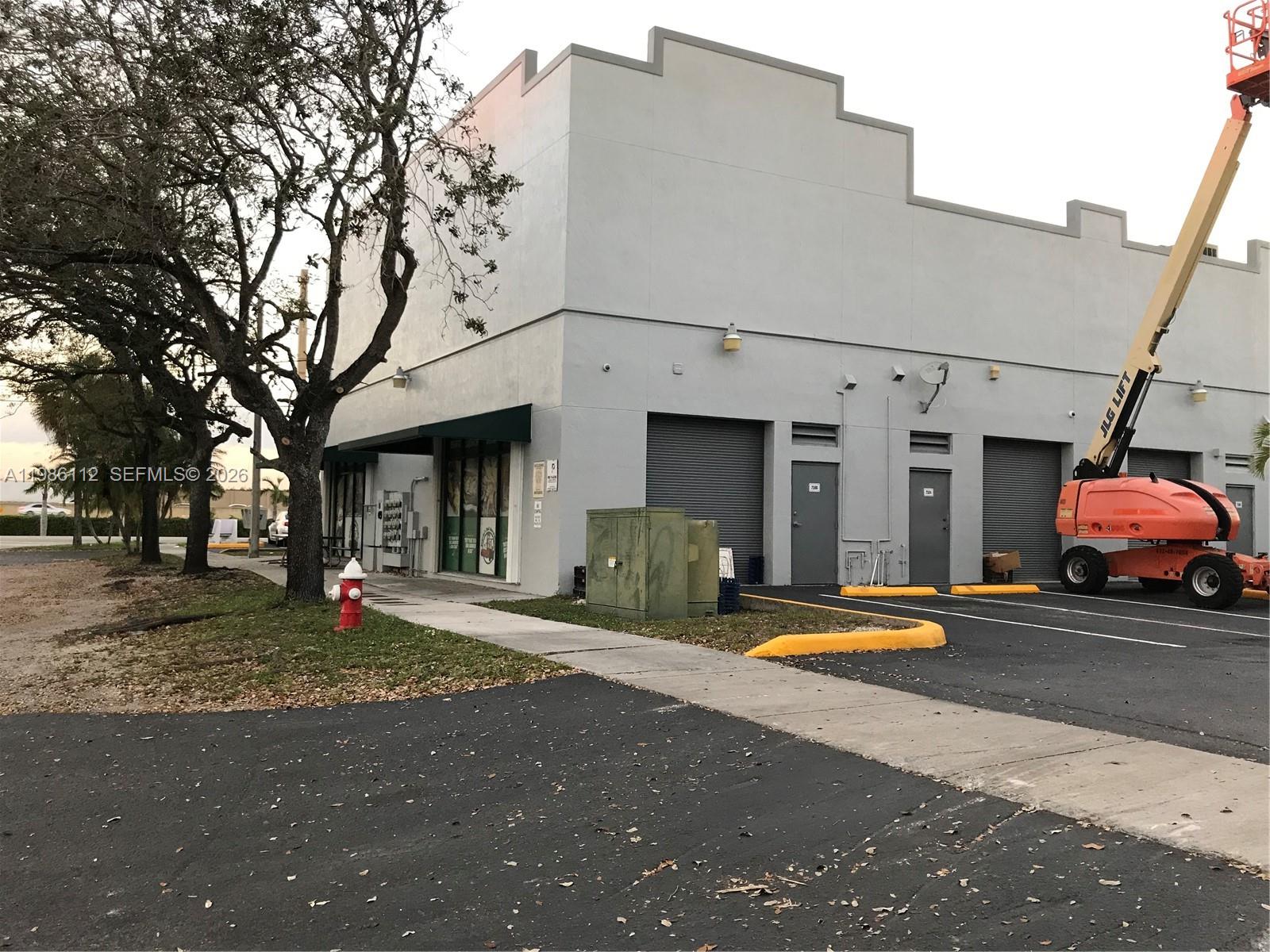 A gray commercial building with a parking lot, a fire hydrant, and a boom lift — 8353 W 26th Ave # B, Hialeah FL 33016, HIALEAH, FL