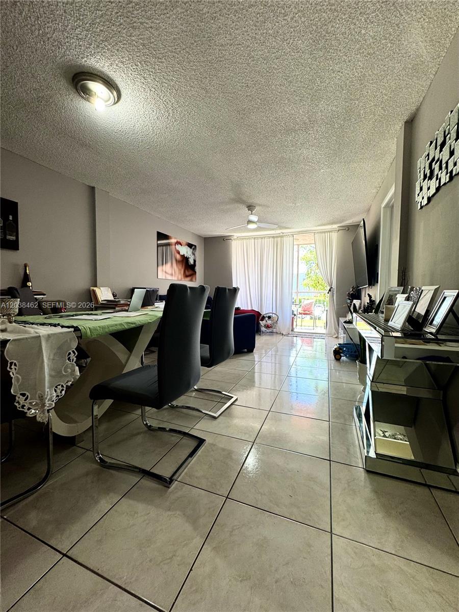 A dining area with tile floors leads to a living space with a balcony view — 19729 SW 114th Ave # 250, Miami FL 33157, MIAMI, FL