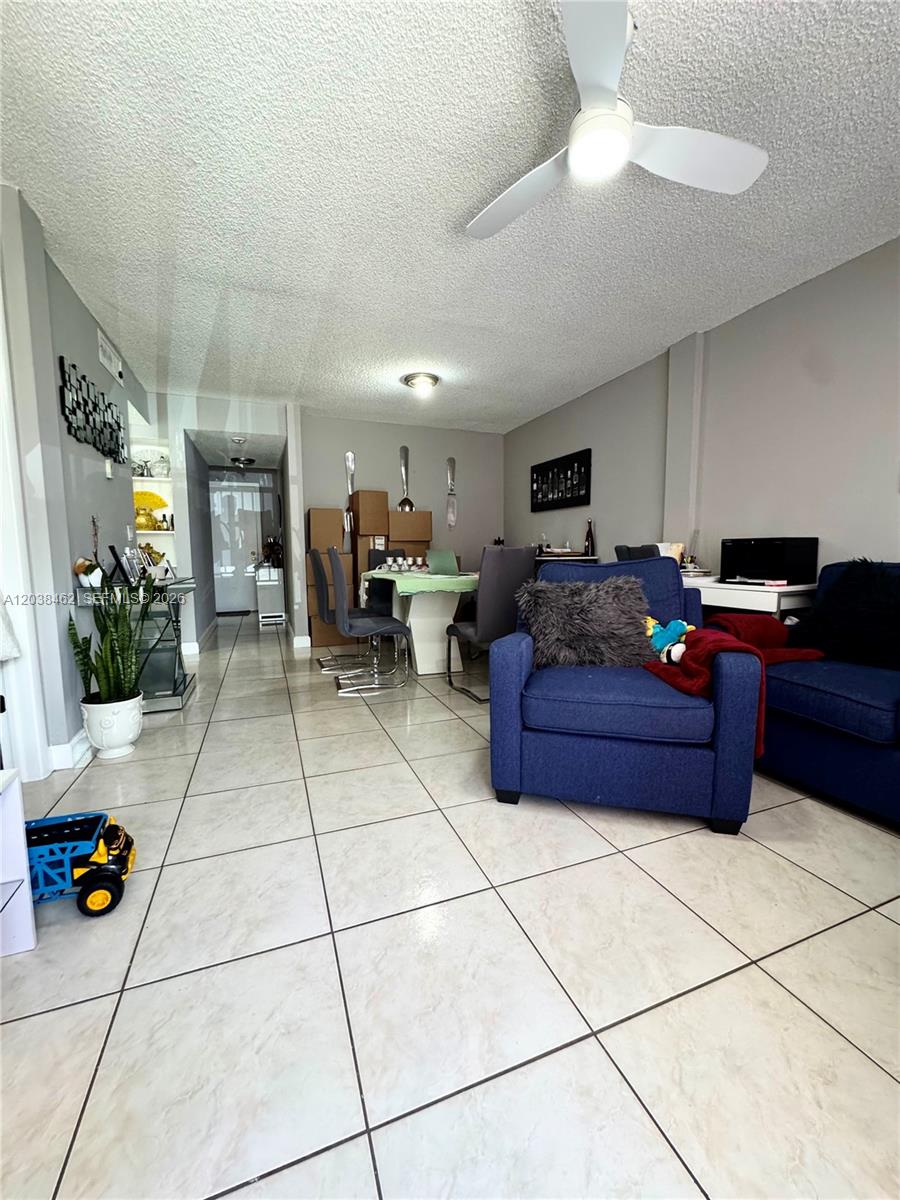 A living and dining area features tile flooring, a ceiling fan, and a blue armchair — 19729 SW 114th Ave # 250, Miami FL 33157, MIAMI, FL