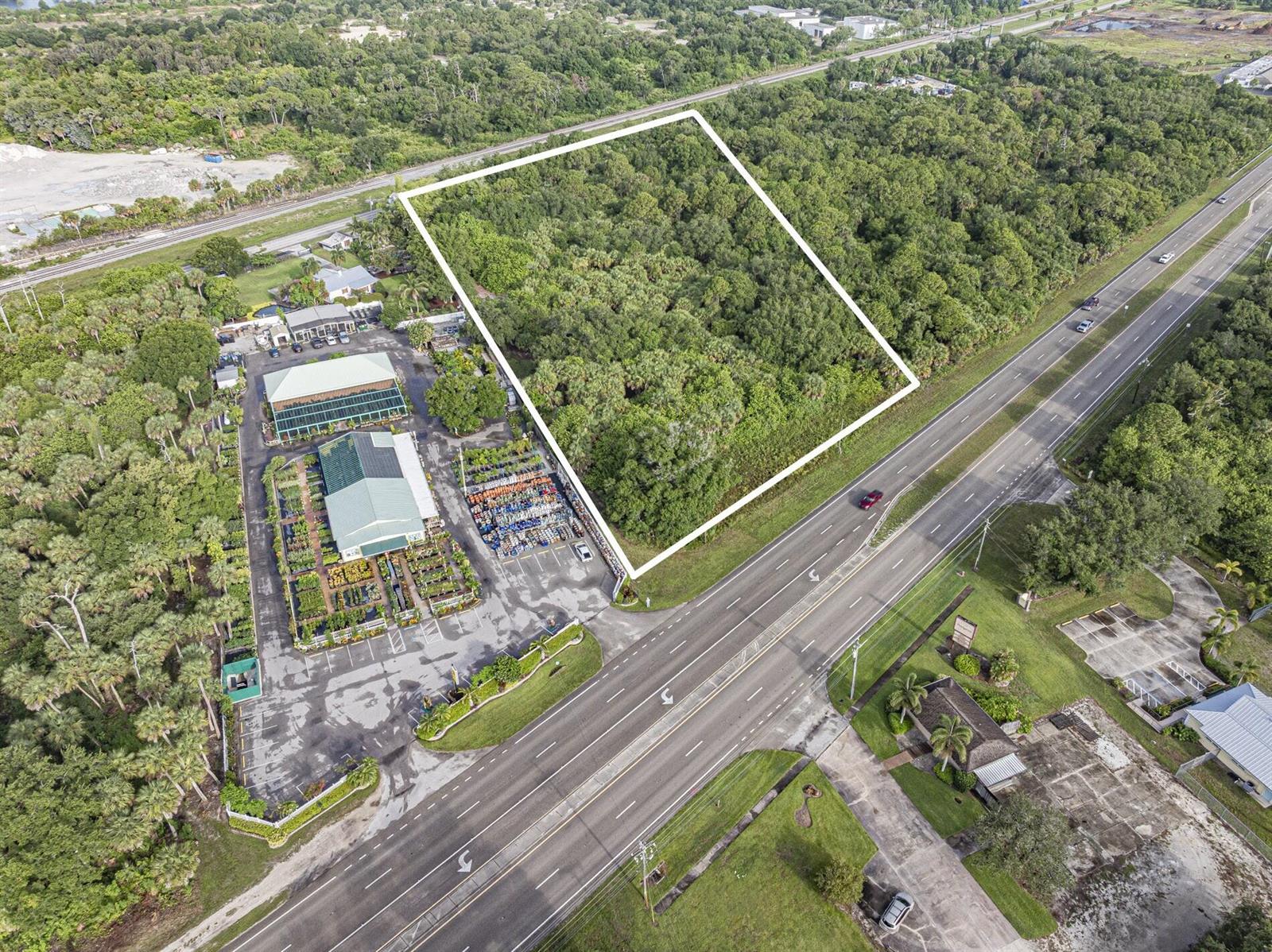 An aerial view shows a rectangular wooded lot outlined in white next to a nursery — 7555 Us Highway 1, Vero Beach FL 32967, VERO BEACH, FL