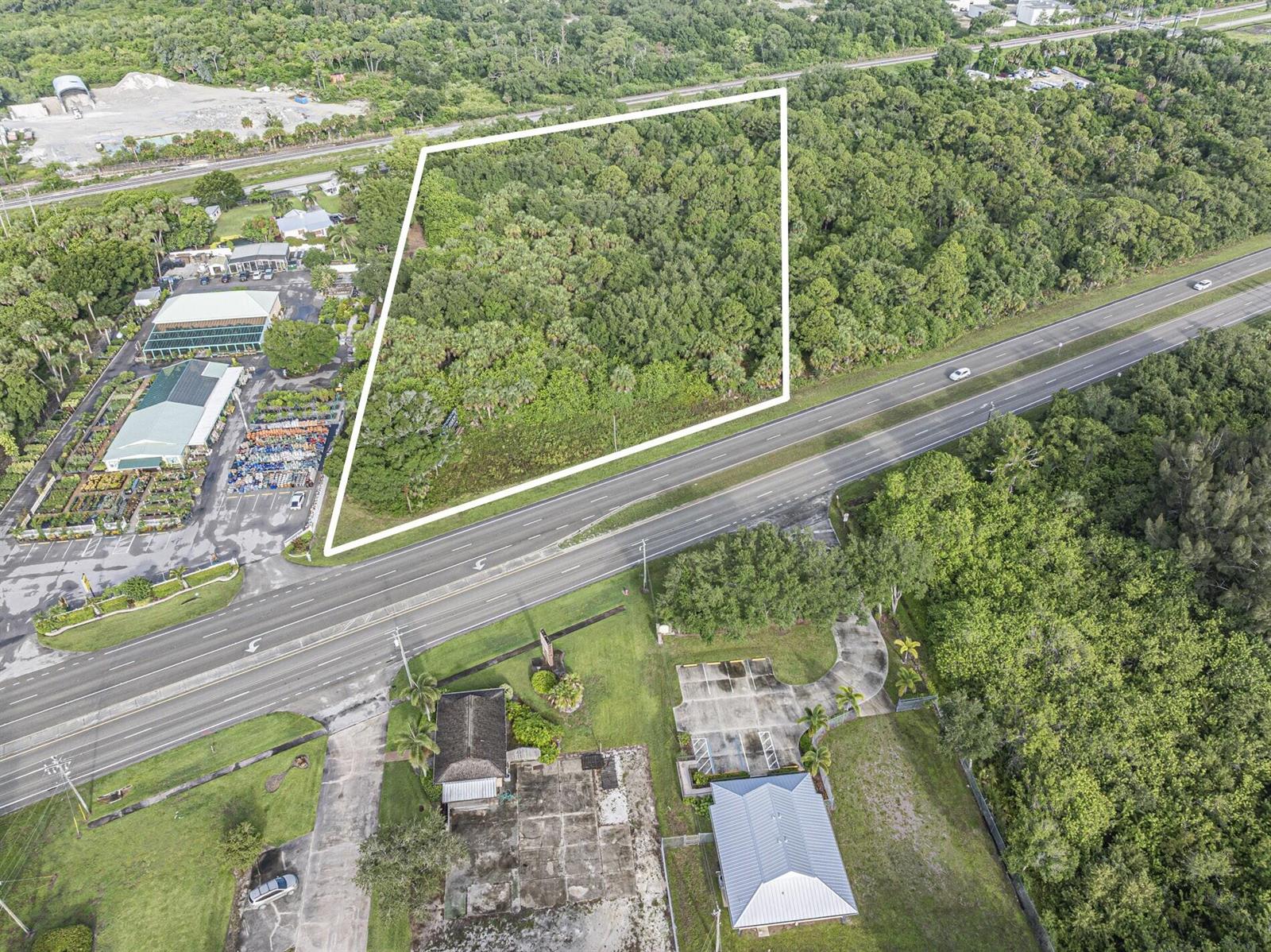An aerial view shows a wooded, trapezoidal plot of land outlined in white near a highway — 7555 Us Highway 1, Vero Beach FL 32967, VERO BEACH, FL