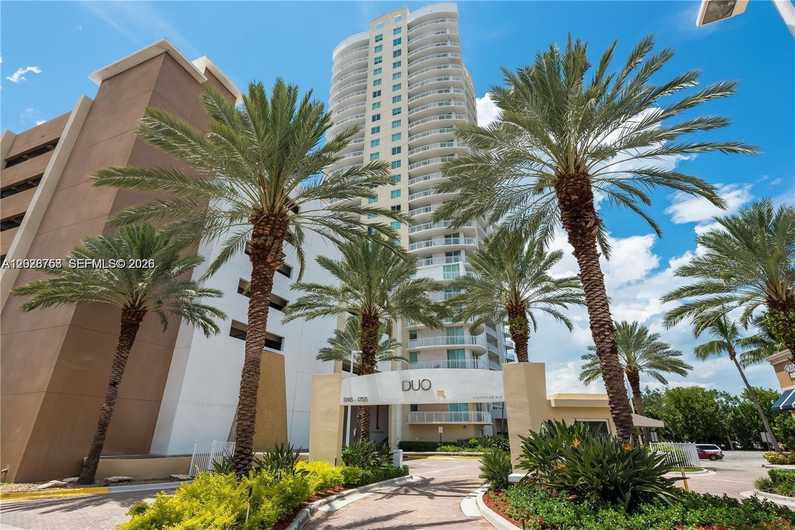 A tall residential tower stands behind a gated entrance with palm trees and landscaping — 1745 E Hallandale Beach Blvd # 2304W, Hallandale Beach FL 33009, HALLANDALE BEACH, FL