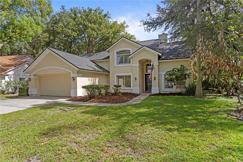 A two-story house with a beige stucco exterior, a two-car garage, and a front lawn — 7210 HAMMET ROAD, TAMPA, FL