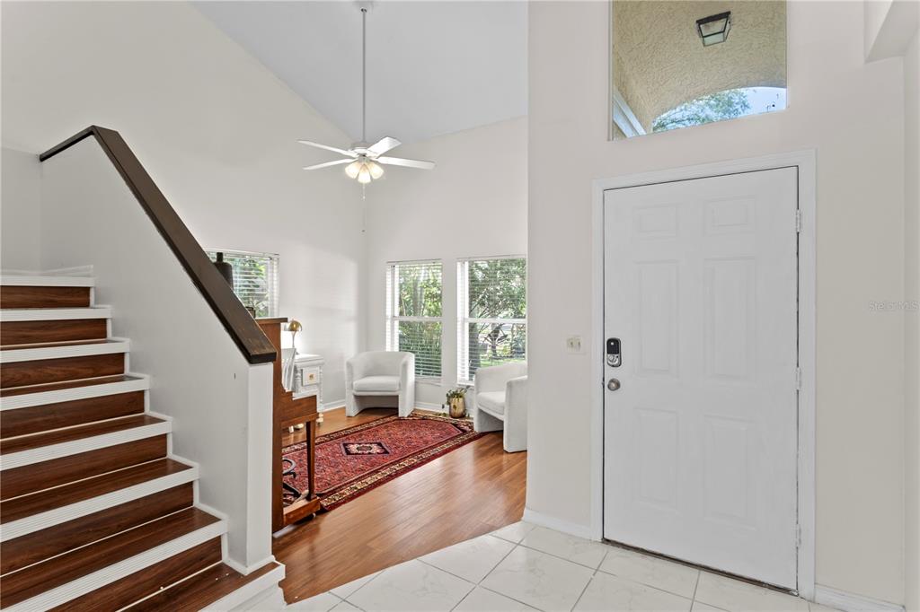 An entryway features a staircase with wood treads, a white door, and a seating area — 7210 HAMMET ROAD, TAMPA, FL