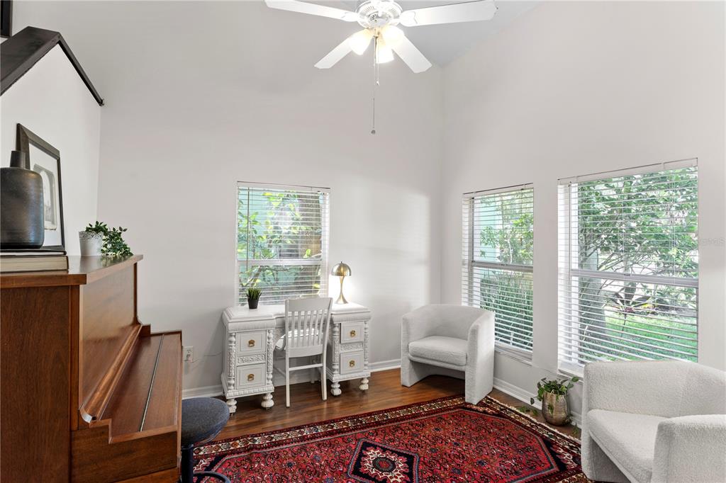 A room with a piano, a white desk, two armchairs, and a large patterned rug — 7210 HAMMET ROAD, TAMPA, FL