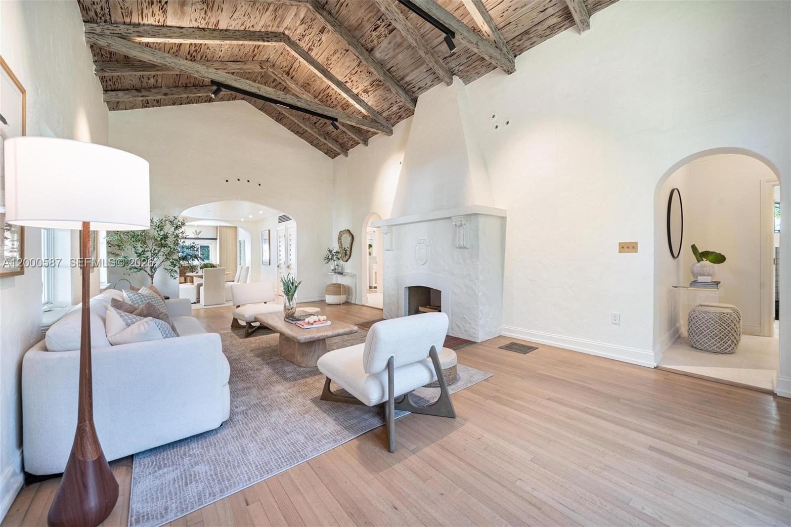 A living room features a vaulted wood-beamed ceiling, a white fireplace, and light hardwood floors — 909 Roderigo Ave, Coral Gables FL 33134, CORAL GABLES, FL