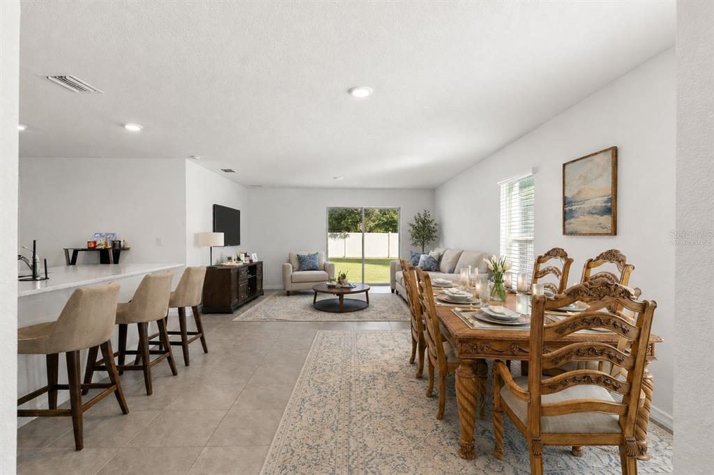 An open-concept living and dining area features tile flooring, a kitchen island, and sliding doors — 37445 SHARKS EYE LANE, ZEPHYRHILLS, FL