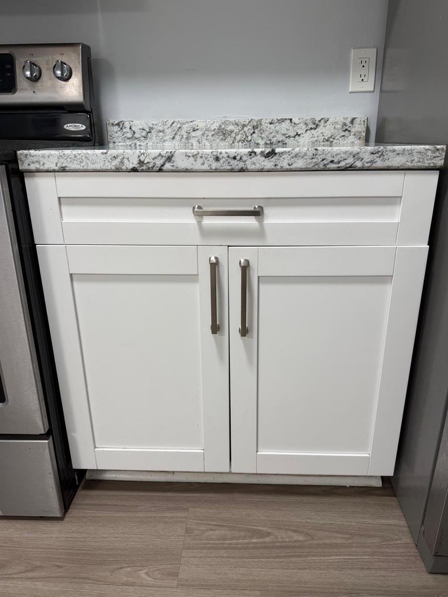 A white kitchen cabinet with a granite countertop sits next to a stainless steel stove — 615 S State Road 7 # 1d, Margate FL 33068, MARGATE, FL