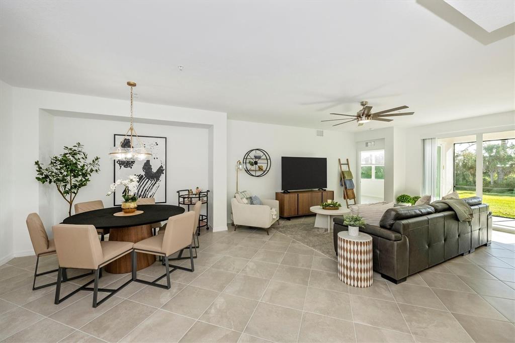 An open-concept living and dining area features tile flooring, a dark sofa, and a table — 17700 BORACAY COURT UNIT 102, VENICE, FL
