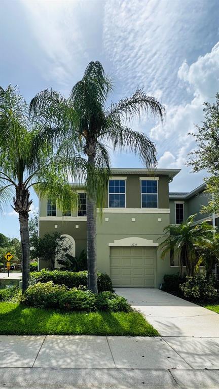 A two-story house with a green exterior, a garage, and palm trees in the front yard — 2939 WILLOWLEAF LANE, WESLEY CHAPEL, FL