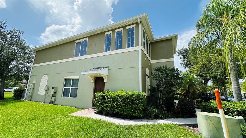 A two-story light green stucco building with a brown front door and a small porch — 2939 WILLOWLEAF LANE, WESLEY CHAPEL, FL