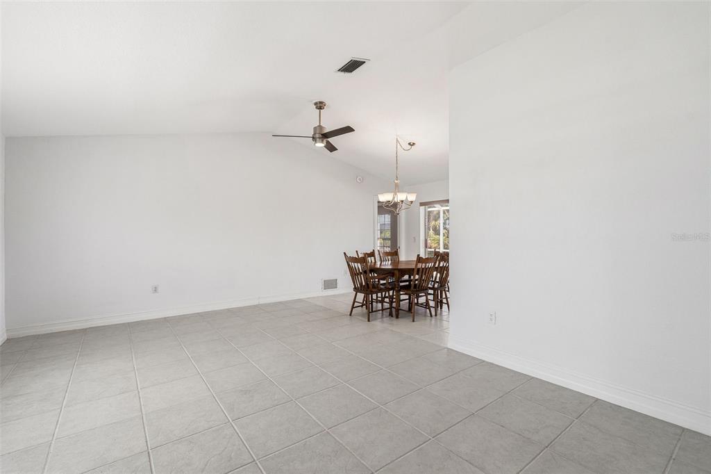 A spacious room with white walls, tile flooring, a ceiling fan, and a dining area — 15184 ALDAMA CIRCLE, PORT CHARLOTTE, FL