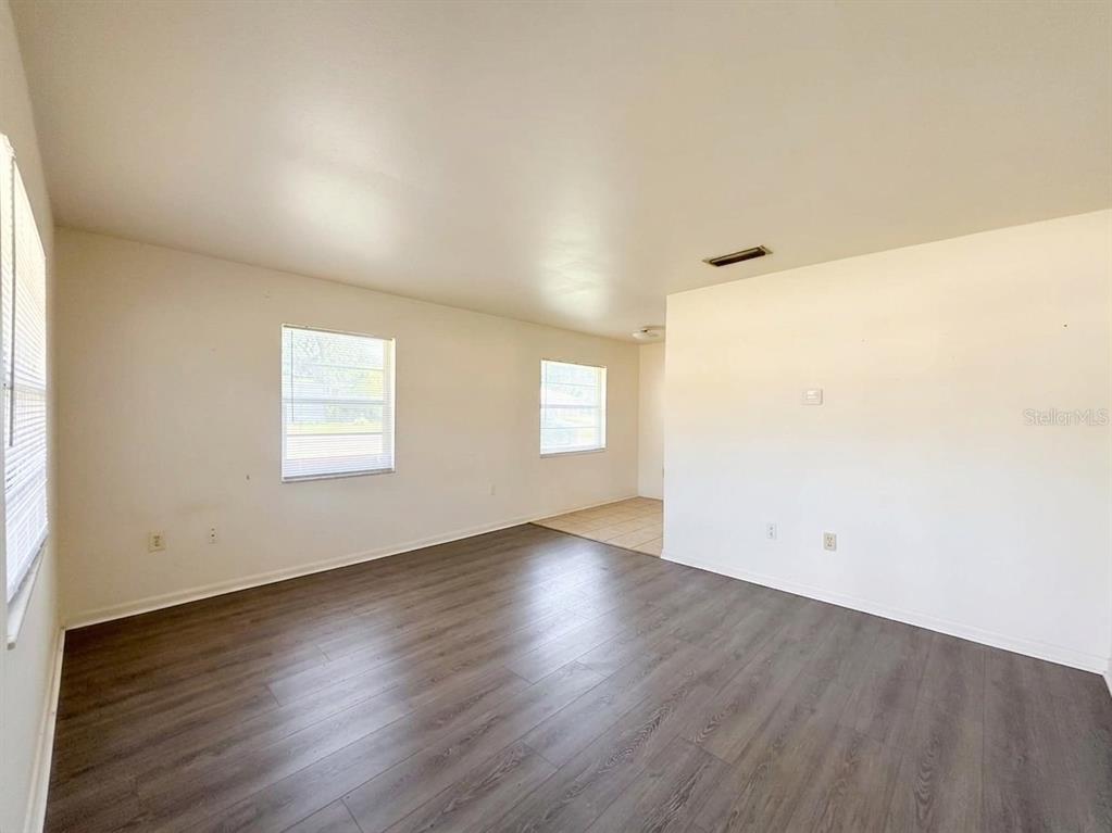 A living room with light-colored walls, dark wood-look flooring, and three windows — 1240 JOSEPHINE STREET, LAKELAND, FL
