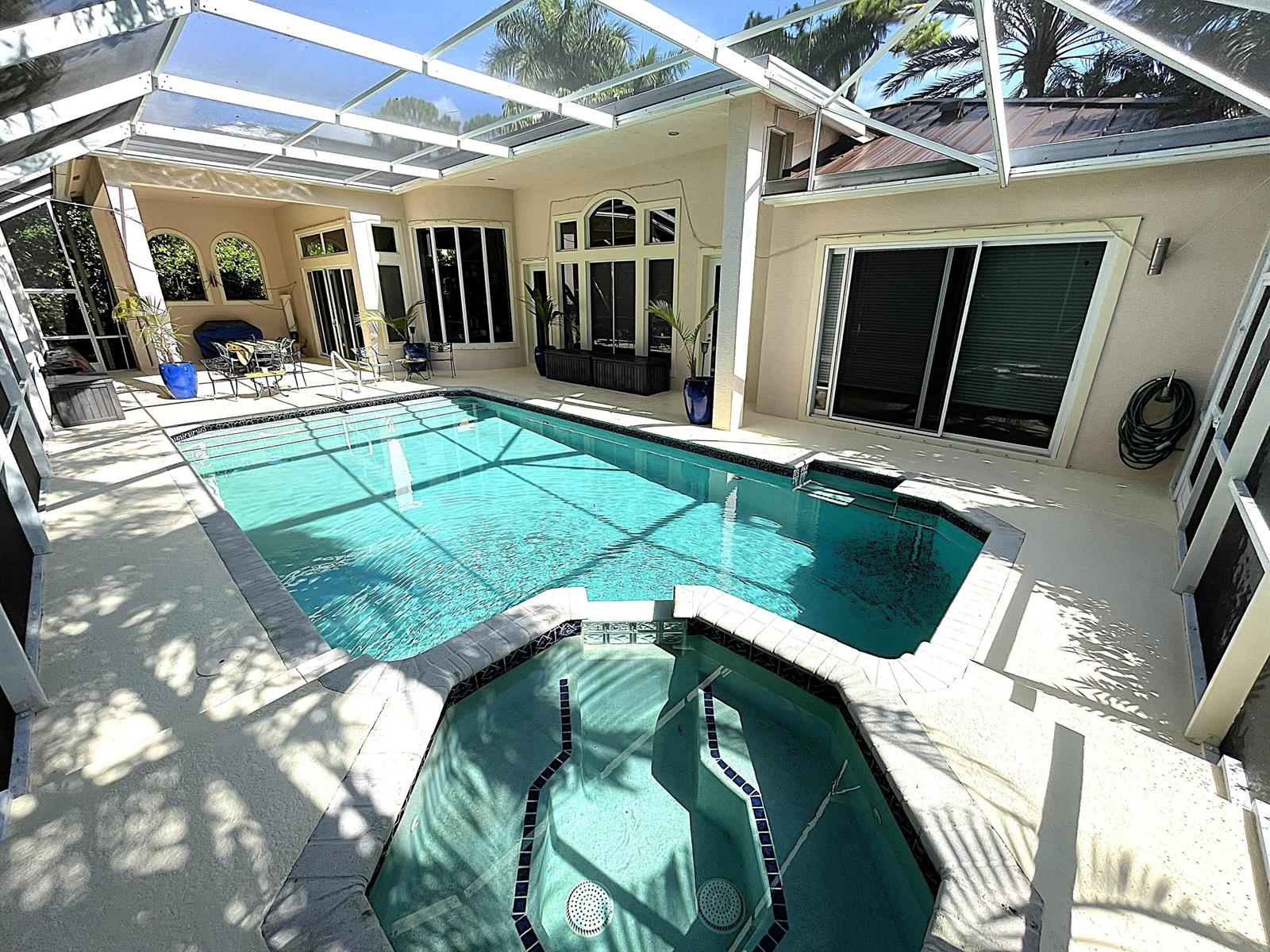 A screened-in patio features a swimming pool and attached hot tub next to a house — 4740 Glenn Pine Lane, Boynton Beach FL 33436, BOYNTON BEACH, FL