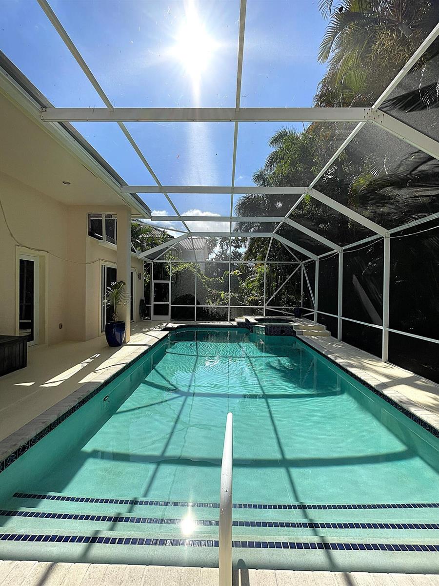 A rectangular swimming pool with a spa is enclosed by a white screen cage — 4740 Glenn Pine Lane, Boynton Beach FL 33436, BOYNTON BEACH, FL