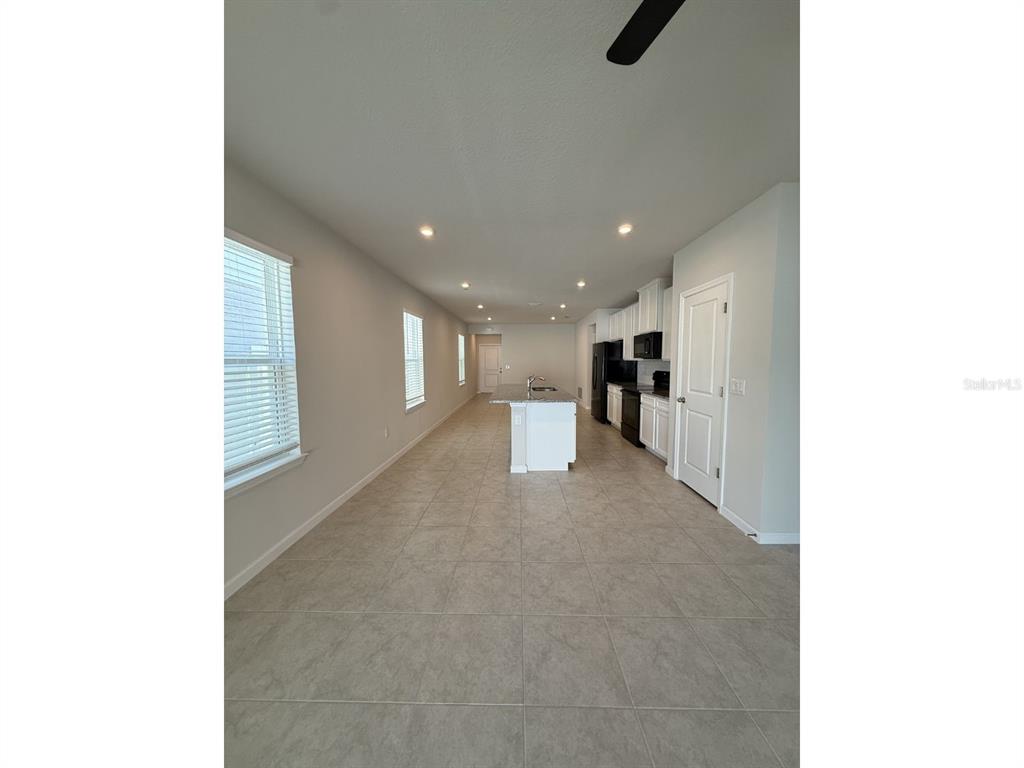 An open-concept kitchen and living area features tile flooring, white cabinets, and a central island — 11921 BRISTOL BRIDGE ROAD, SPRING HILL, FL