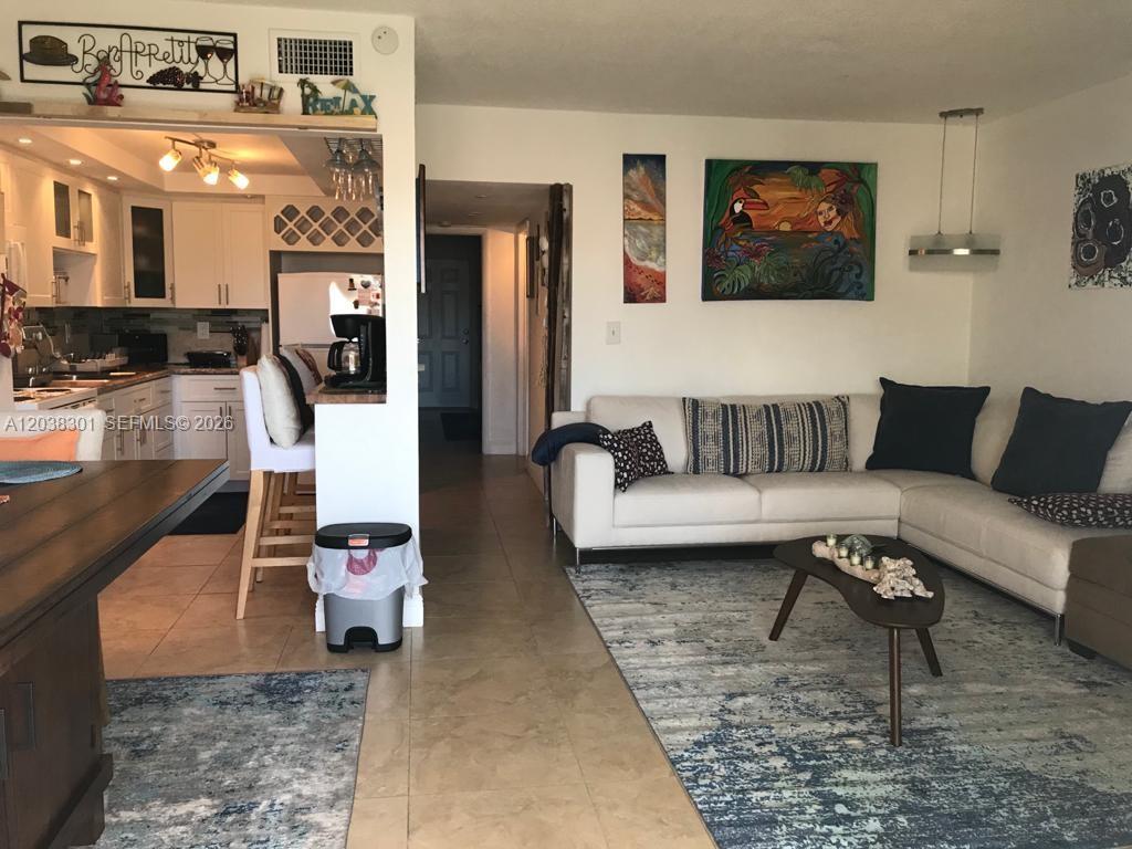 A living room with a white sectional sofa connects to an open kitchen with bar seating — 320 S Surf Rd # 305, Hollywood FL 33019, HOLLYWOOD, FL