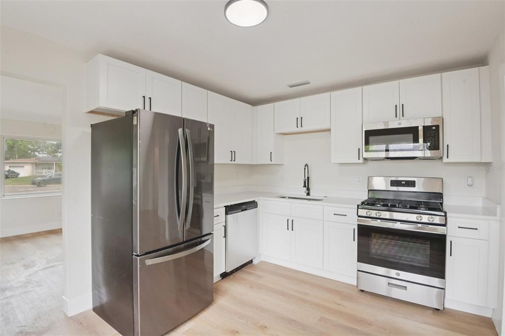 A kitchen with white cabinets, stainless steel appliances, and light wood-look flooring — 3468 9TH AVENUE N, ST PETERSBURG, FL