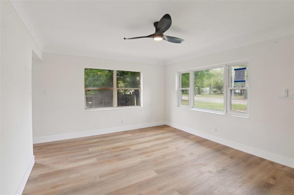 An empty room with light wood-look flooring, white walls, and a modern ceiling fan — 3468 9TH AVENUE N, ST PETERSBURG, FL