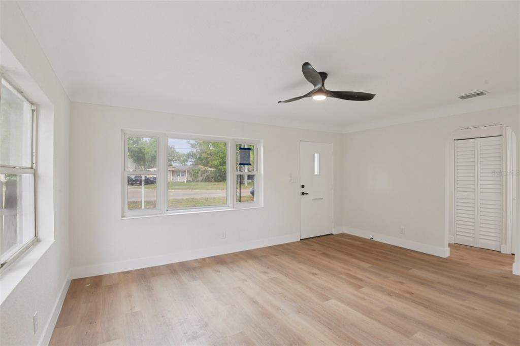An empty room with light wood-look flooring, white walls, a ceiling fan, and a front door — 3468 9TH AVENUE N, ST PETERSBURG, FL