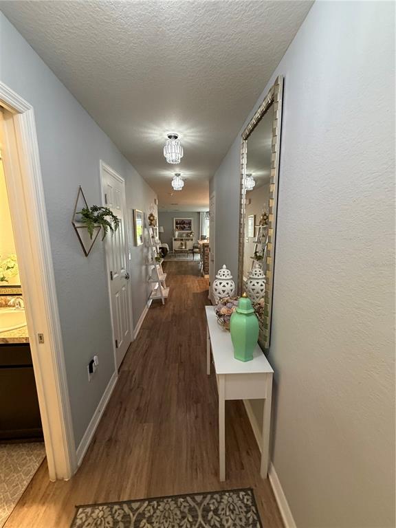 A hallway with wood-look flooring leads toward an open living area with a console table — 3024 FIELDWOOD CIRCLE, ST CLOUD, FL
