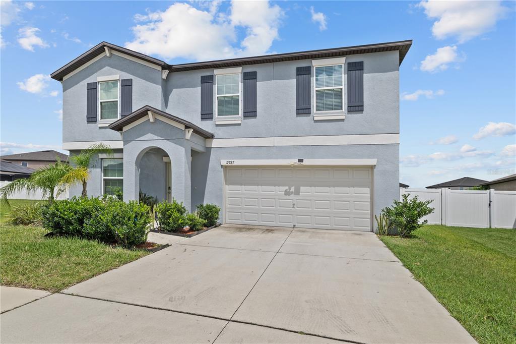 A two-story house with a light blue stucco exterior, a two-car garage, and shutters — 12787 MAPLE BONSAI DRIVE, RIVERVIEW, FL