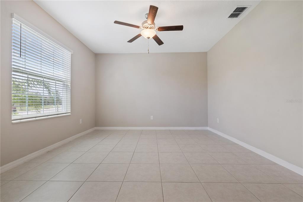 An empty room with beige walls, light tile flooring, and a ceiling fan — 12787 MAPLE BONSAI DRIVE, RIVERVIEW, FL