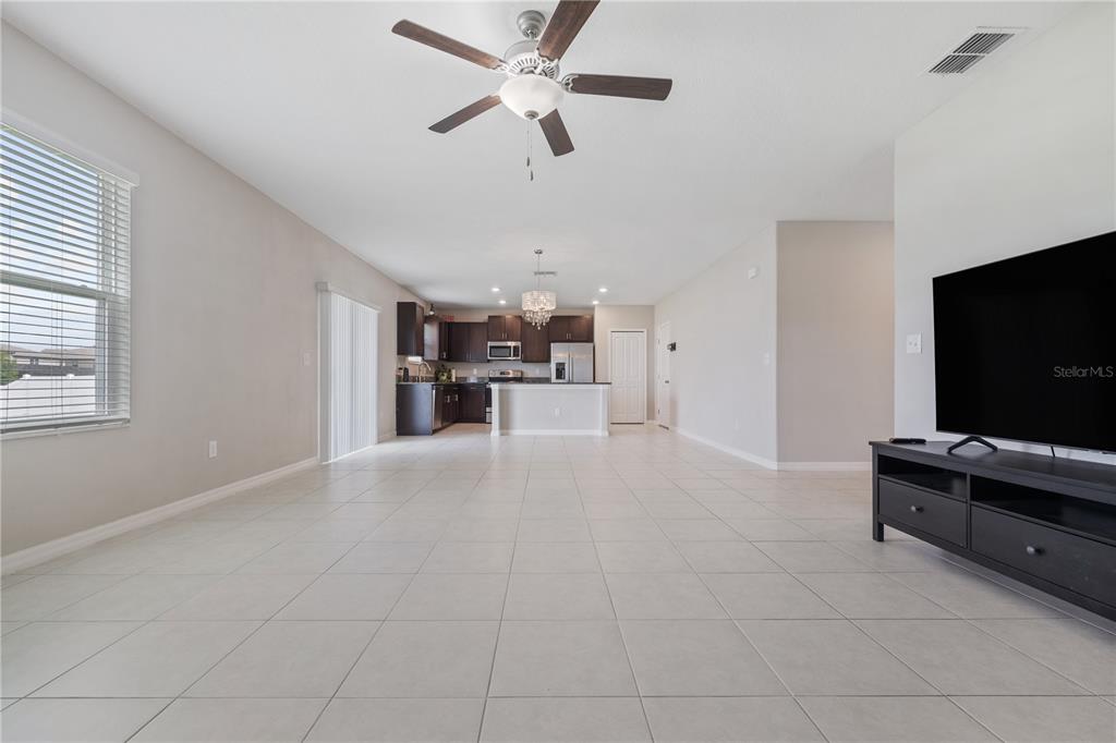 A spacious living room with tile flooring leads to an open kitchen with dark cabinets — 12787 MAPLE BONSAI DRIVE, RIVERVIEW, FL