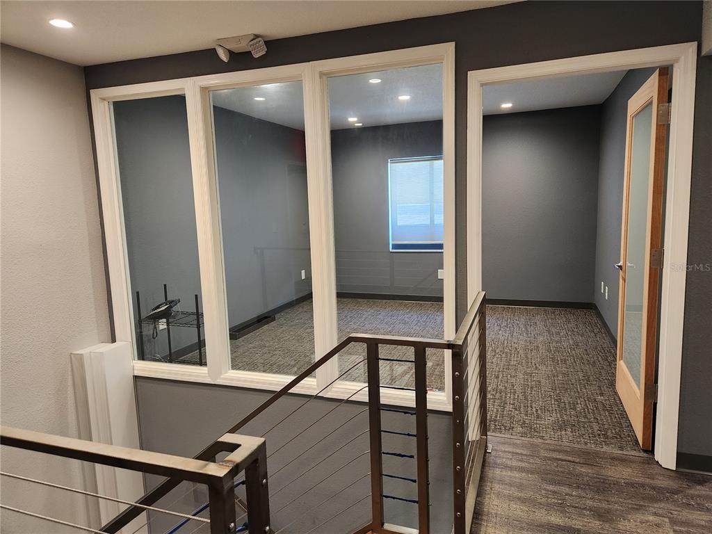 An office space with glass walls, gray carpet, and a wooden door overlooks a staircase — 4409 W EL PRADO BOULEVARD, TAMPA, FL