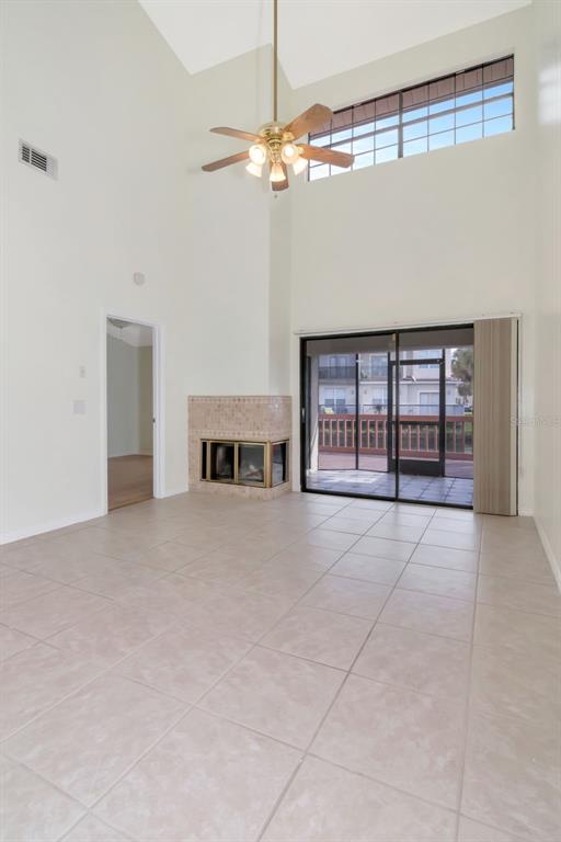 A living room with tile flooring, a fireplace, a ceiling fan, and sliding glass doors — 10417 SAINT TROPEZ PLACE UNIT 103, TAMPA, FL