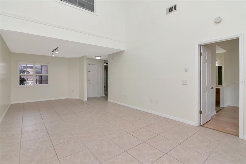 An empty room with light-colored tile flooring, high ceilings, and a doorway leading to a bathroom — 10417 SAINT TROPEZ PLACE UNIT 103, TAMPA, FL