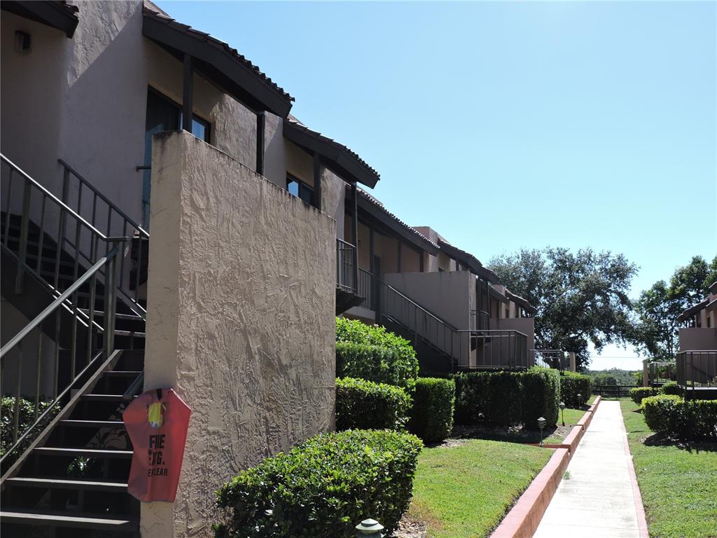 An exterior view of a multi-story apartment building with stairs and a concrete walkway — 133 LA CASA UNIT 133, LAKE WALES, FL