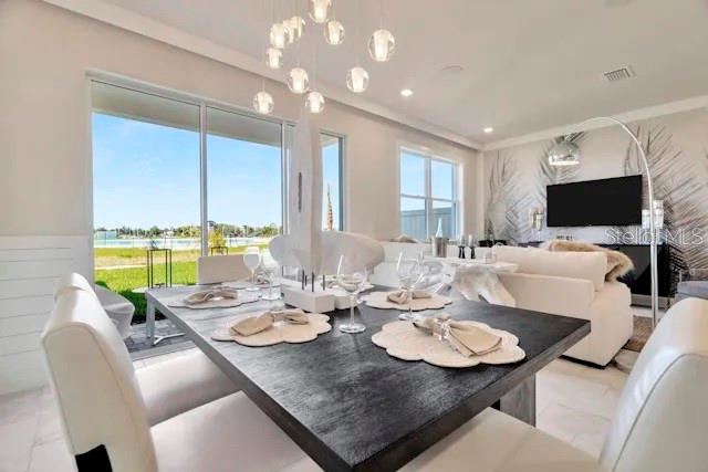 A dining room with a dark wooden table, white chairs, and a view of a lake — 31844 CLOVER FIN COURT, WESLEY CHAPEL, FL