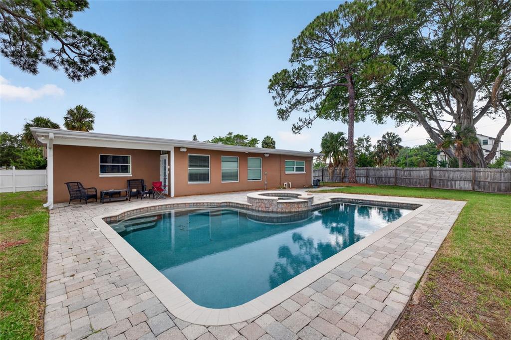 A backyard features a swimming pool with an attached spa and a paved patio area — 4627 VENETIAN BOULEVARD NE, ST PETERSBURG, FL