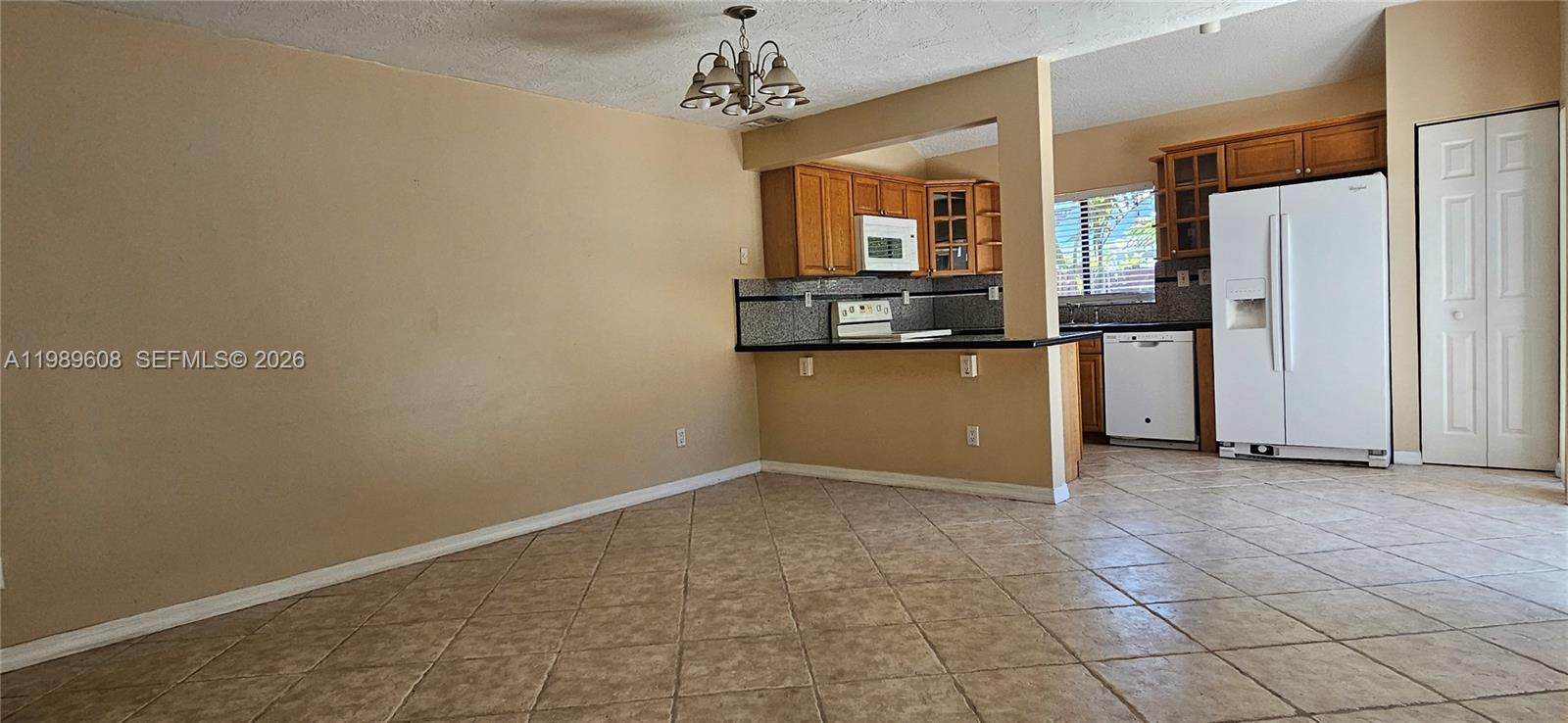 This kitchen and dining area features tile flooring, wood cabinets, and a white refrigerator — 610 Commodore Dr, Plantation FL 33325, PLANTATION, FL